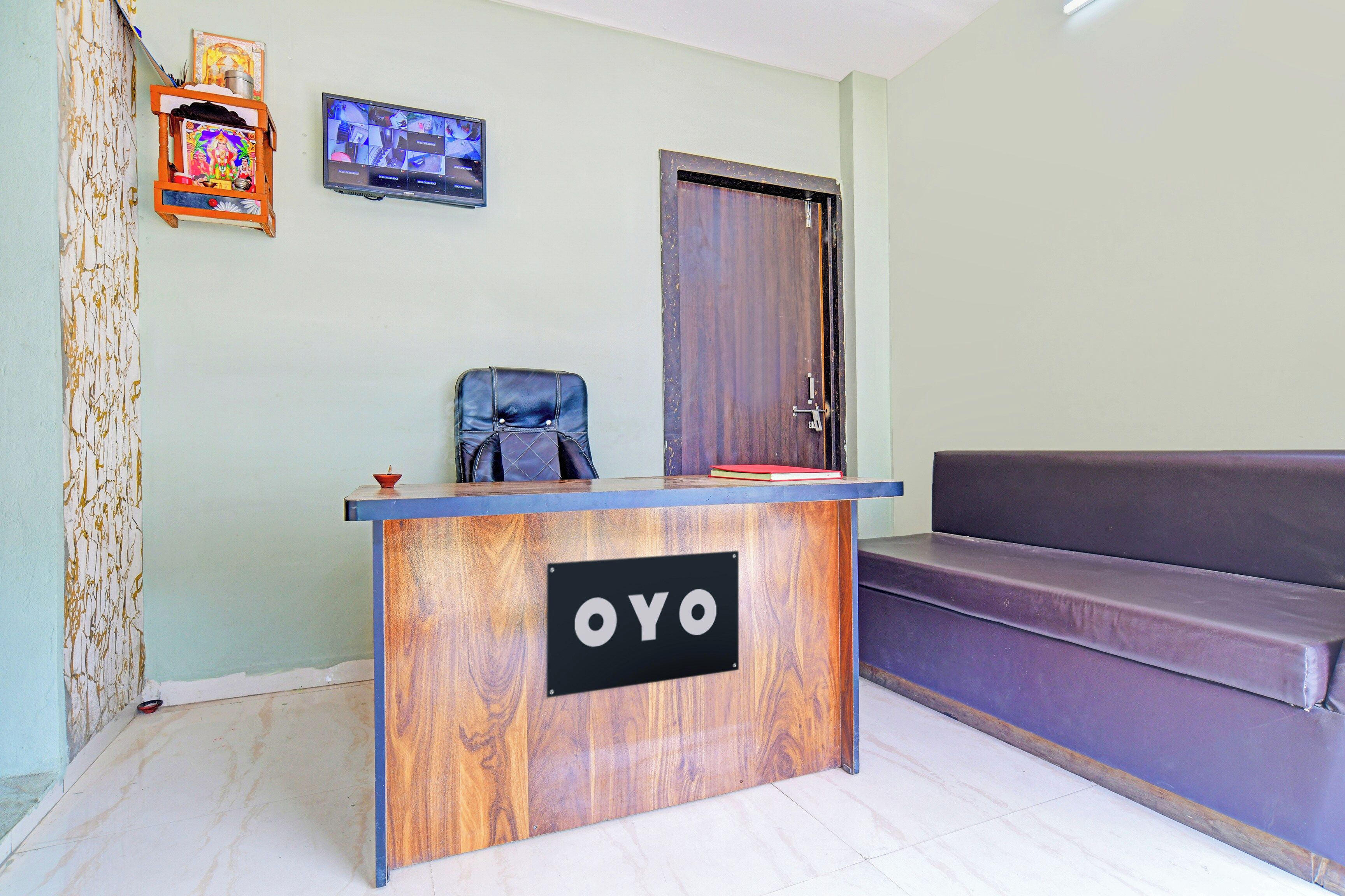 Bancada de recepção com acabamento em madeira e uma placa com a inscrição 'OYO'.