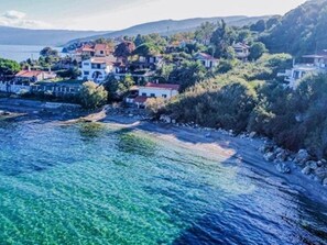 A coastal town with buildings along the shoreline, clear blue water, and hills in the background. - Holiday Home 'Art Of Luxury Superior Villa' with Sea View, Private Terrace and Air Conditioning (Κάτω Πολυδένδρι)