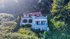 A two-story house with a red roof, surrounded by dense greenery. - Holiday Home 'Art Of Luxury Superior Villa' with Sea View, Private Terrace and Air Conditioning (Κάτω Πολυδένδρι)
