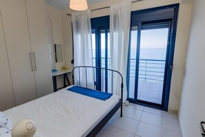 A bedroom with a bed, a wardrobe, a desk, and a view of the sea through a door. - Holiday Home 'Art Of Luxury Superior Villa' with Sea View, Private Terrace and Air Conditioning (Κάτω Πολυδένδρι)