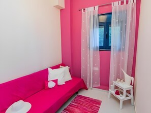 A room with a pink sofa, a white chair, a small table, and a window with sheer curtains. - Holiday Home 'Art Of Luxury Superior Villa' with Sea View, Private Terrace and Air Conditioning (Κάτω Πολυδένδρι)