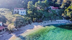 A coastal property with a beach, a house with a red roof, and dense vegetation. - Holiday Home 'Art Of Luxury' with Sea View, Private Terrace and Air Conditioning (Κάτω Πολυδένδρι)