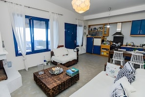 Ein modernes Wohnzimmer mit Sofa, Couchtisch und Essbereich, im Hintergrund eine Küche.