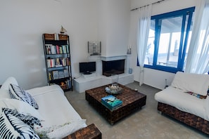 Ein Wohnzimmer mit Kamin, Bücherregal und großem Fenster.