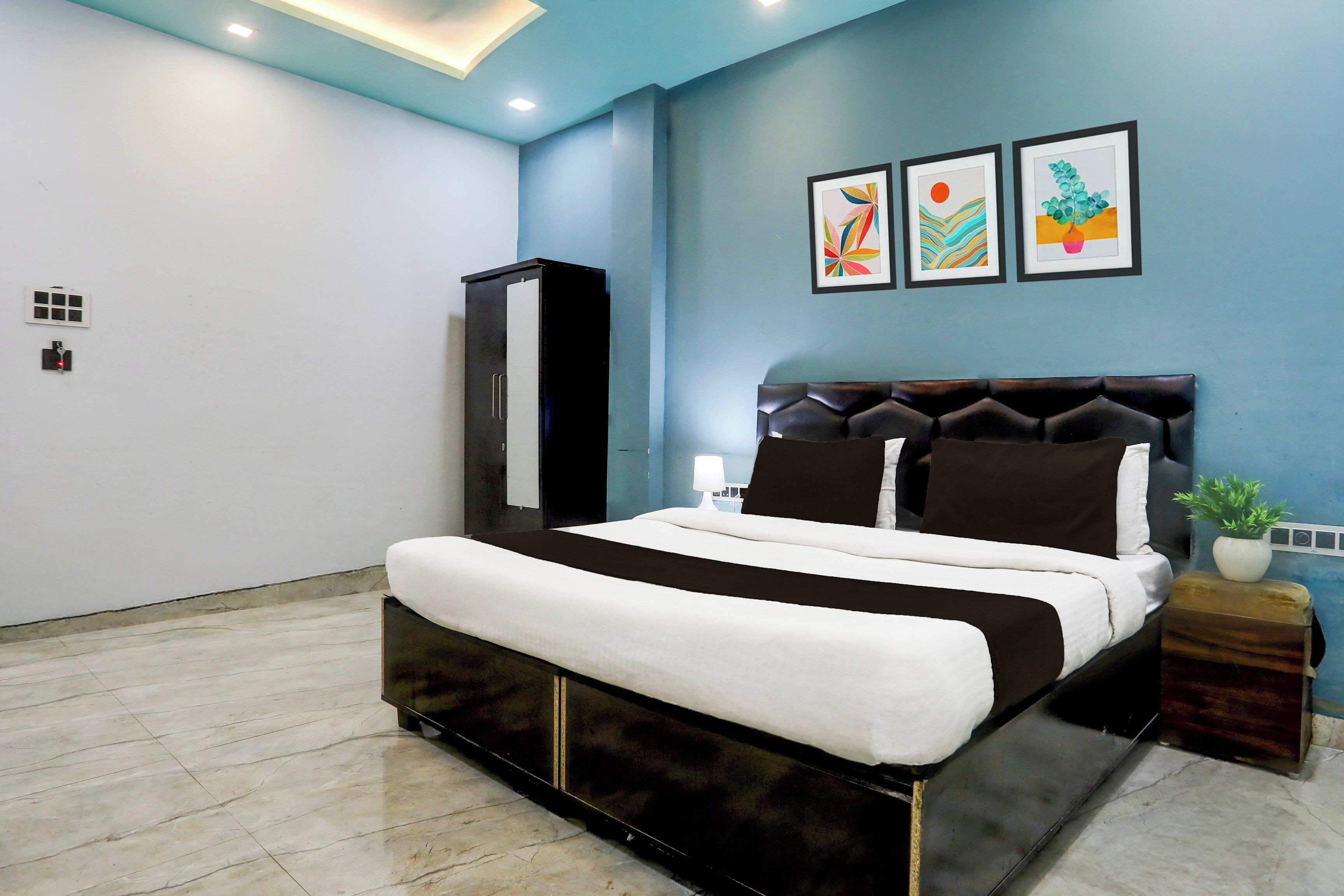 Quarto moderno com cama, guarda-roupa, mesa de cabeceira e planta em vaso.