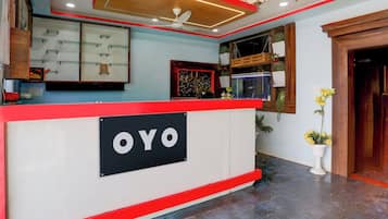 Bancada de recepção com uma placa indicando 'OYO' no saguão de um hotel.