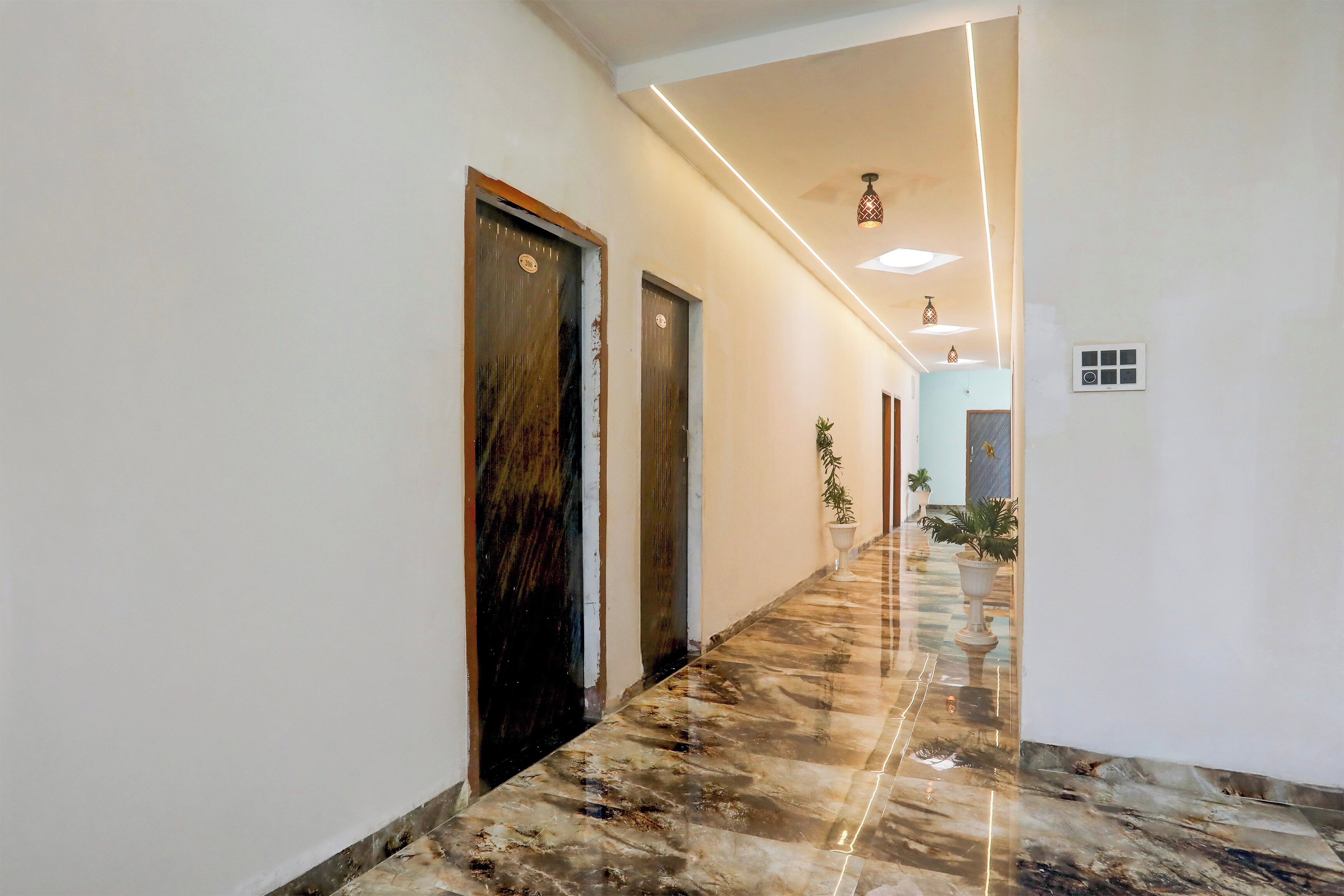 Um corredor com piso de mármore, portas e plantas em vasos.