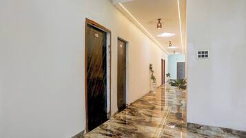 Um corredor com piso de mármore, portas e plantas em vasos.