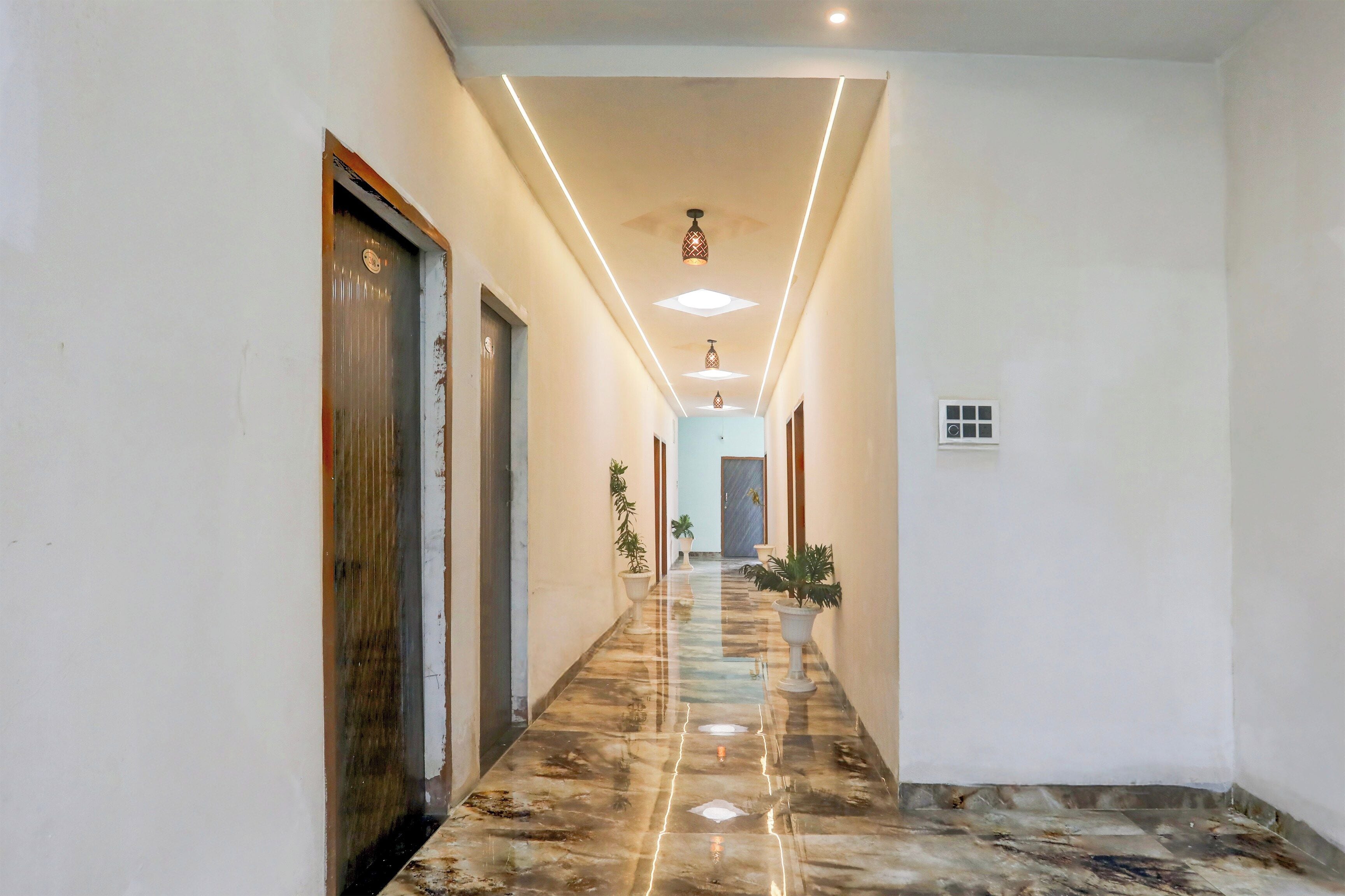 A hotel hallway with a marble floor, doors on both sides, and pendant lighting.