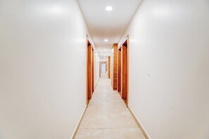 Un pasillo con paredes blancas y paneles de madera a los lados, que conduce a una puerta al final.
