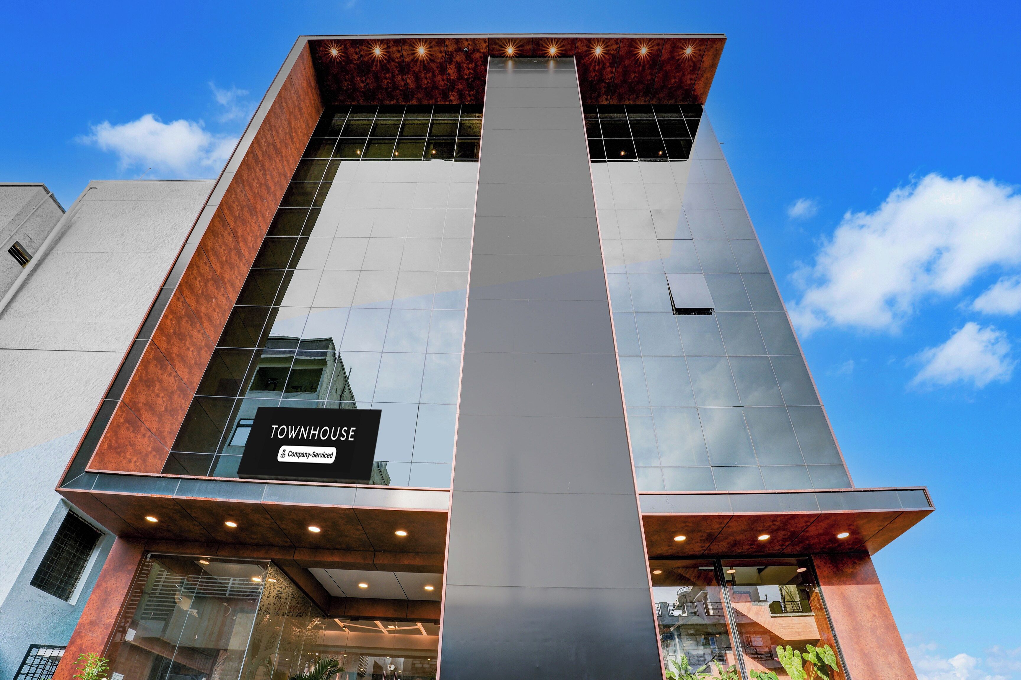 A modern building with a prominent vertical glass facade and a sign reading 'TOWNHOUSE & Company-Serviced'.