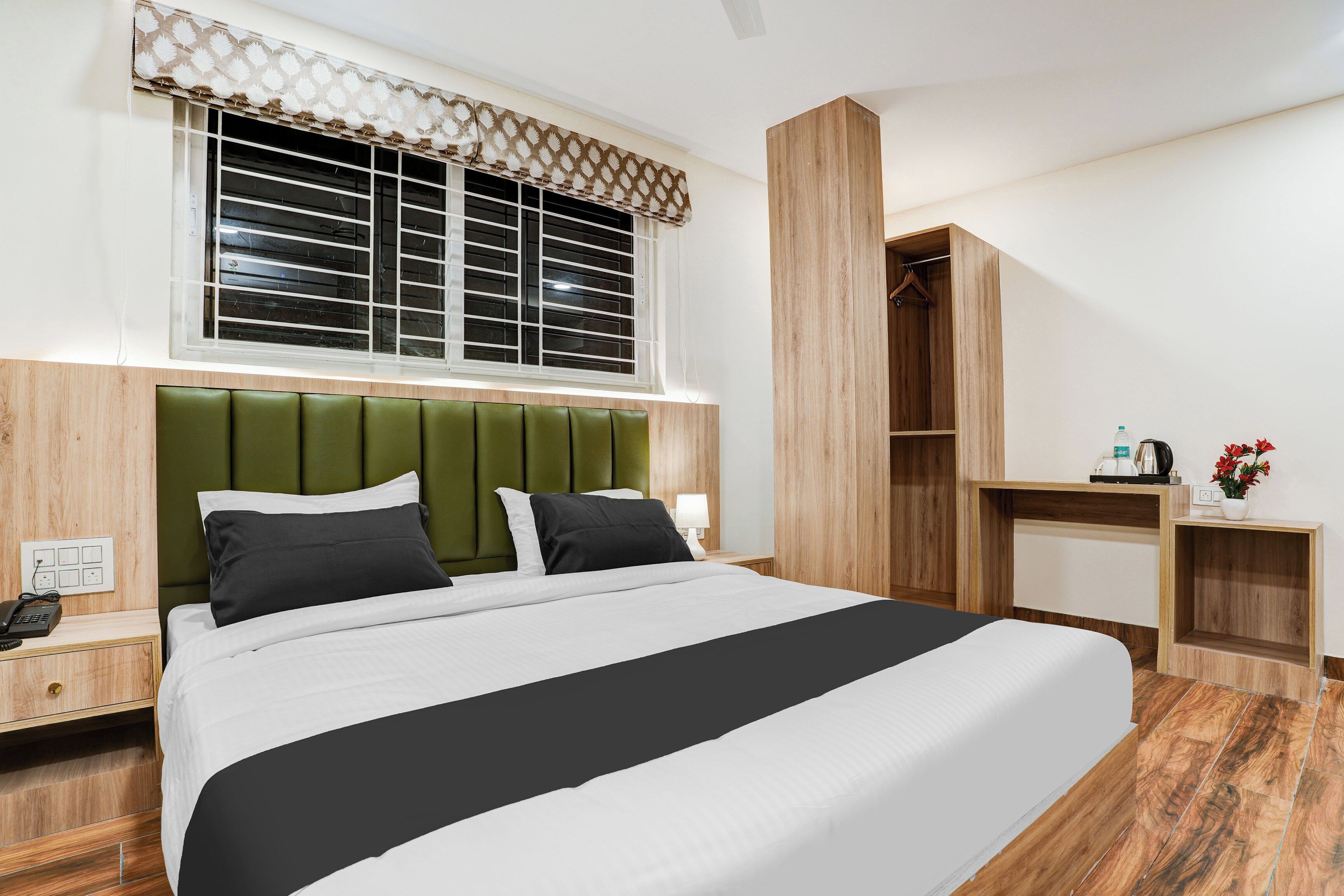 Una habitación de hotel con cama, mesita de noche, lámpara y armario.