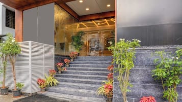 Una escalera conduce a la entrada de un edificio, con plantas en macetas y una reja de metal.