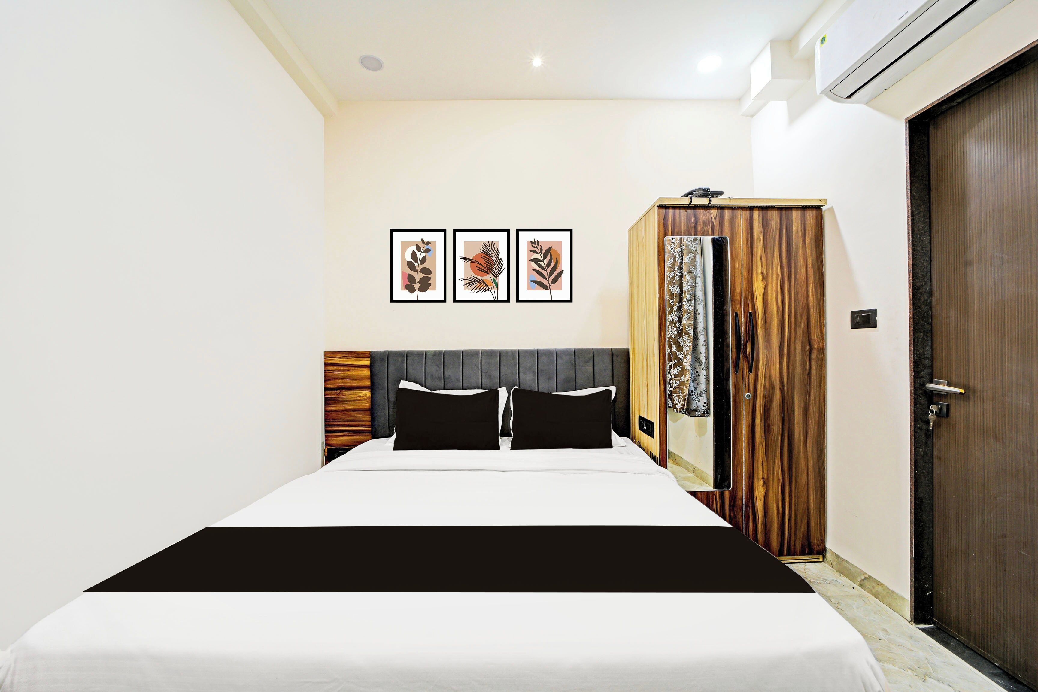 Una habitación de hotel con una cama, un armario y tres cuadros en la pared.