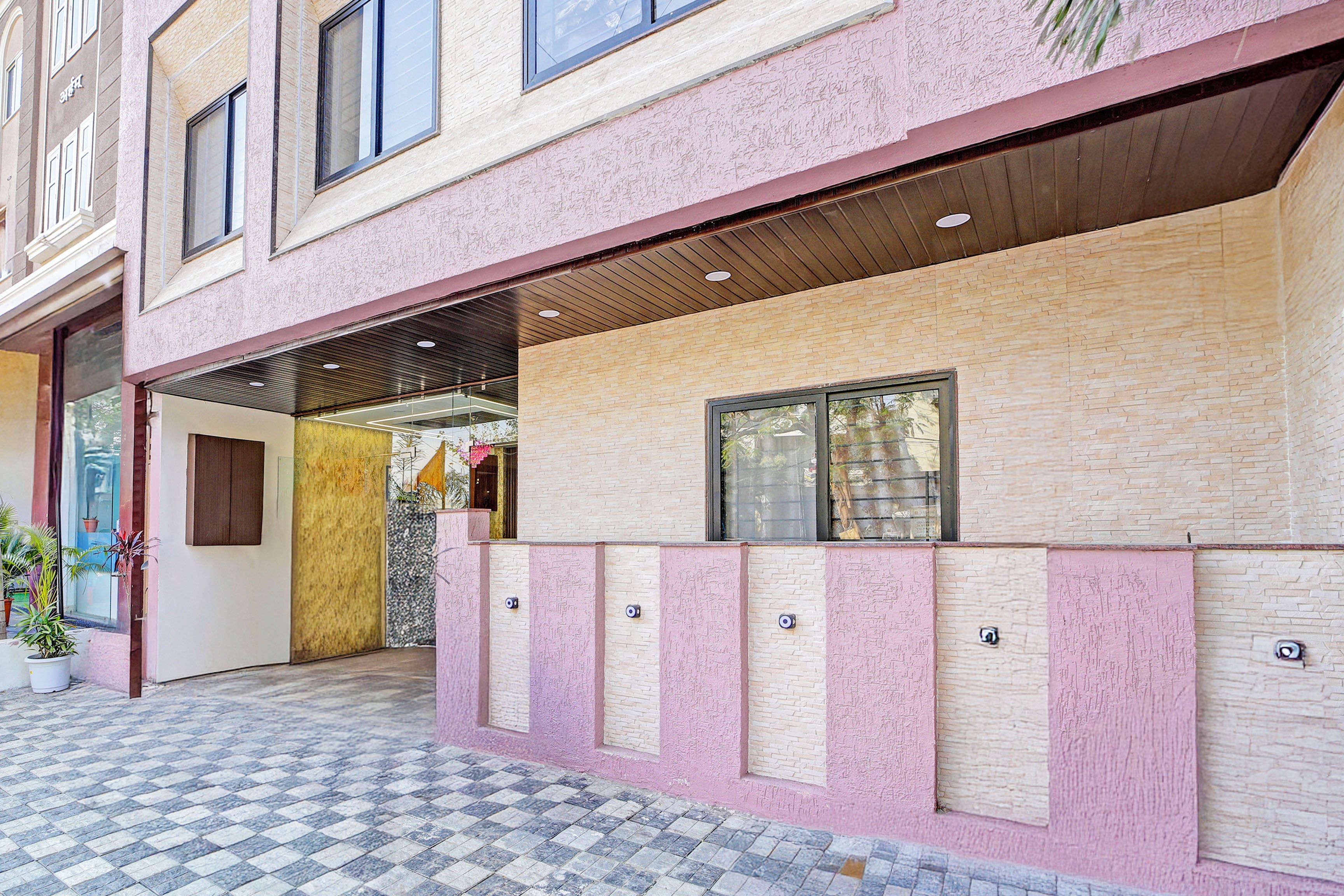 Un edificio con fachada rosa, entrada con baldosas y un ventanal visible.