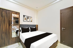 A bedroom with a bed, a wardrobe, a mirror, and three framed pictures on the wall.