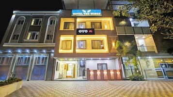 Un hotel con un letrero llamativo que dice 'HOTEL THE WINGS' y 'OYO Hotel The Wings' debajo.