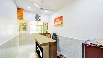 Zona de recepción con mostrador, un reloj y un ventilador de techo.