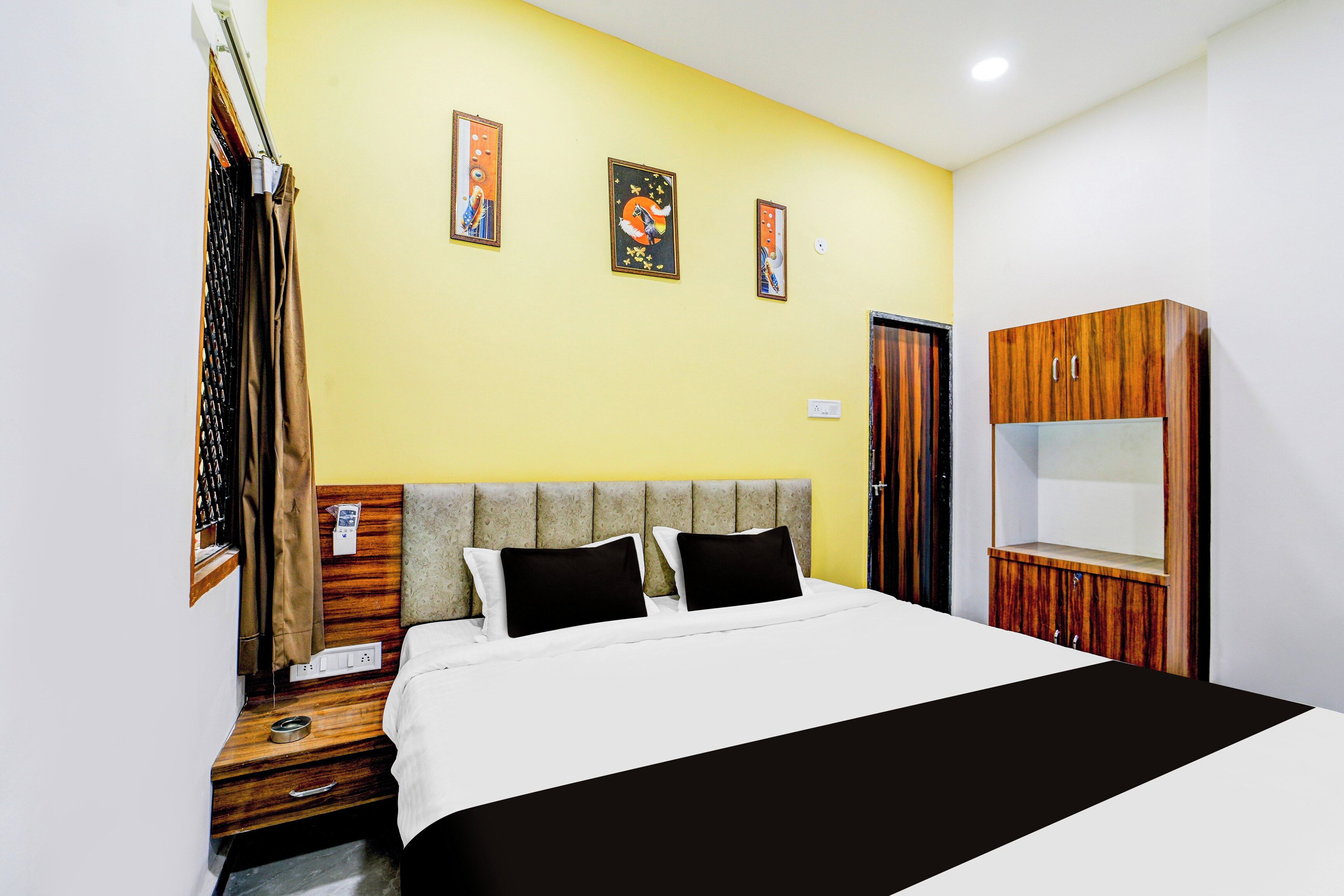 Una habitación de hotel con una cama, un armario de madera y una pared con tres cuadros enmarcados.
