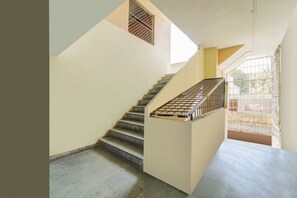 A staircase with a metal handrail and a view of the outside through a barred window. - Hotel O katyayani (Indore)
