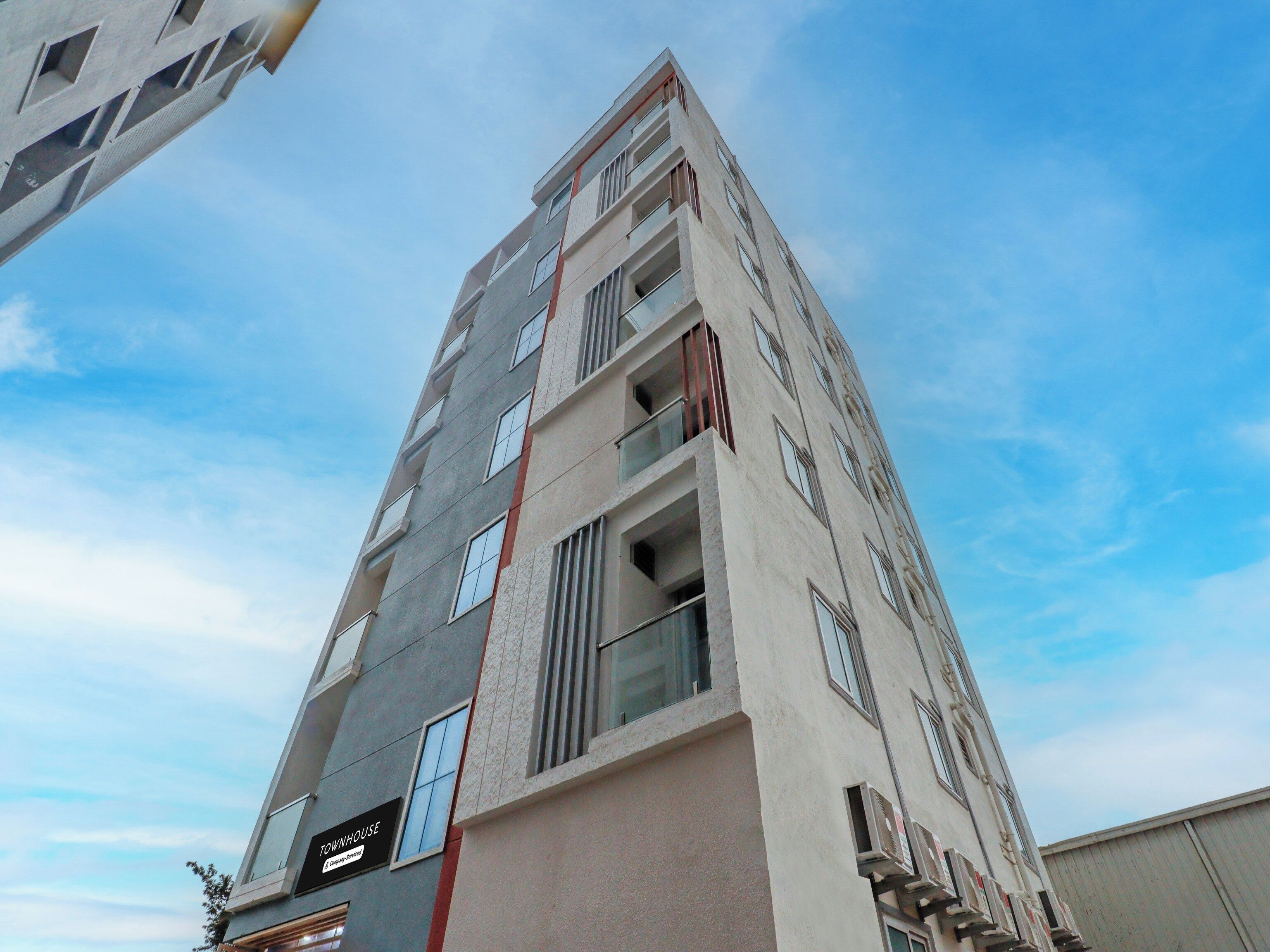 Un edificio de varios pisos con un llamativo letrero 'TOWNHOUSE', ventanas grandes y un diseño arquitectónico moderno.