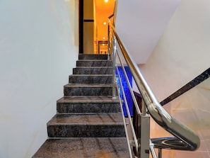 Una escalera con barandilla metálica que lleva a un cuarto con un objeto azul.
