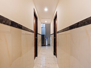 Un pasillo con paredes y puertas de mármol que conduce a una escalera.