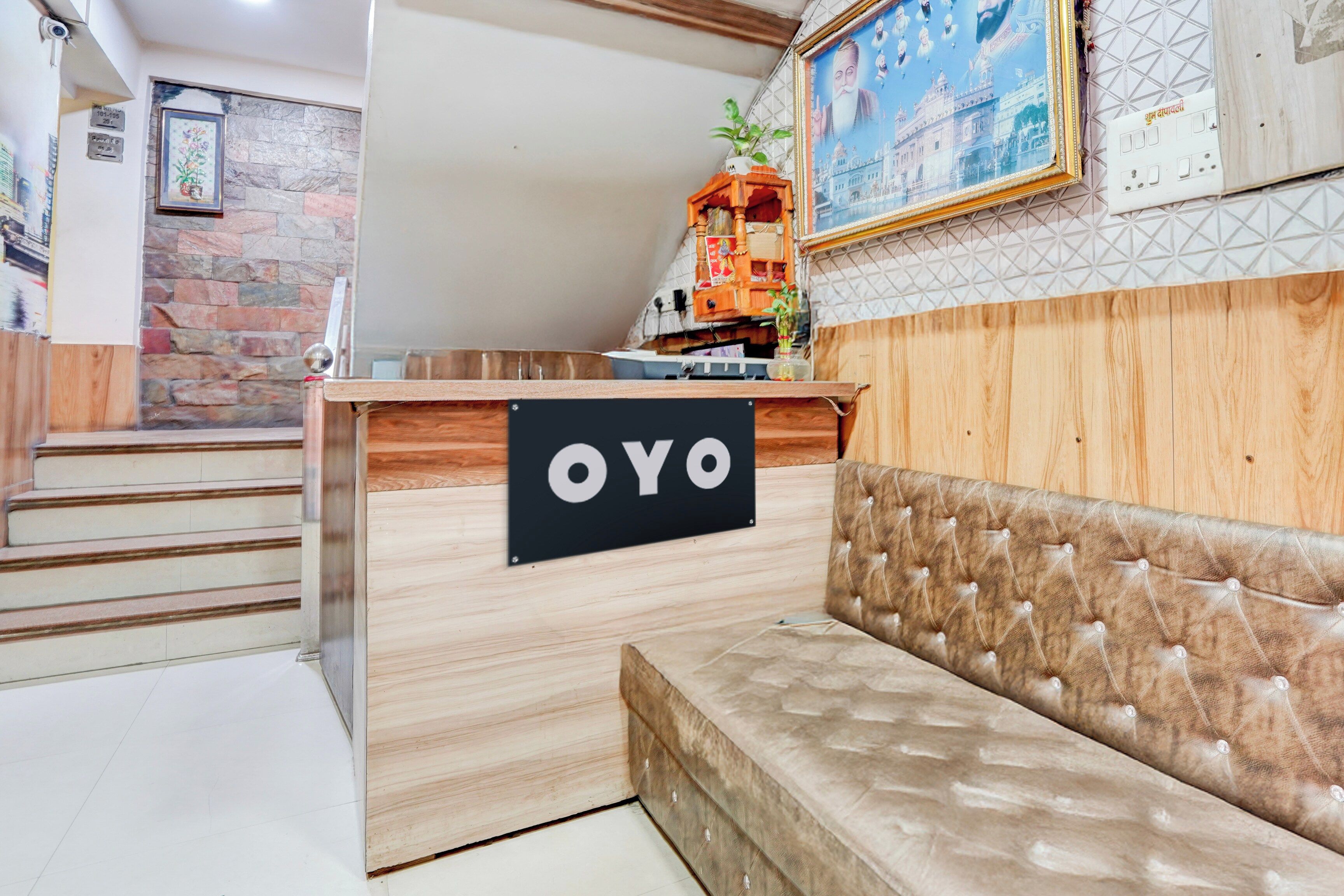 A reception desk with a sign that reads 'OYO' and a plush sofa in the foreground.