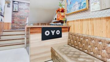 A reception desk with a sign that reads 'OYO' and a plush sofa in the foreground.