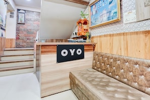 En reception med et skilt der står 'OYO' og en blød sofa forgrunden.