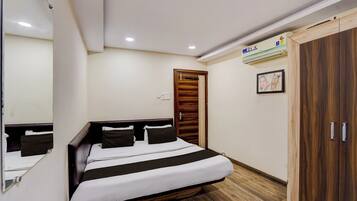 A bedroom with a bed, a wardrobe, a mirror, and an air conditioning unit.