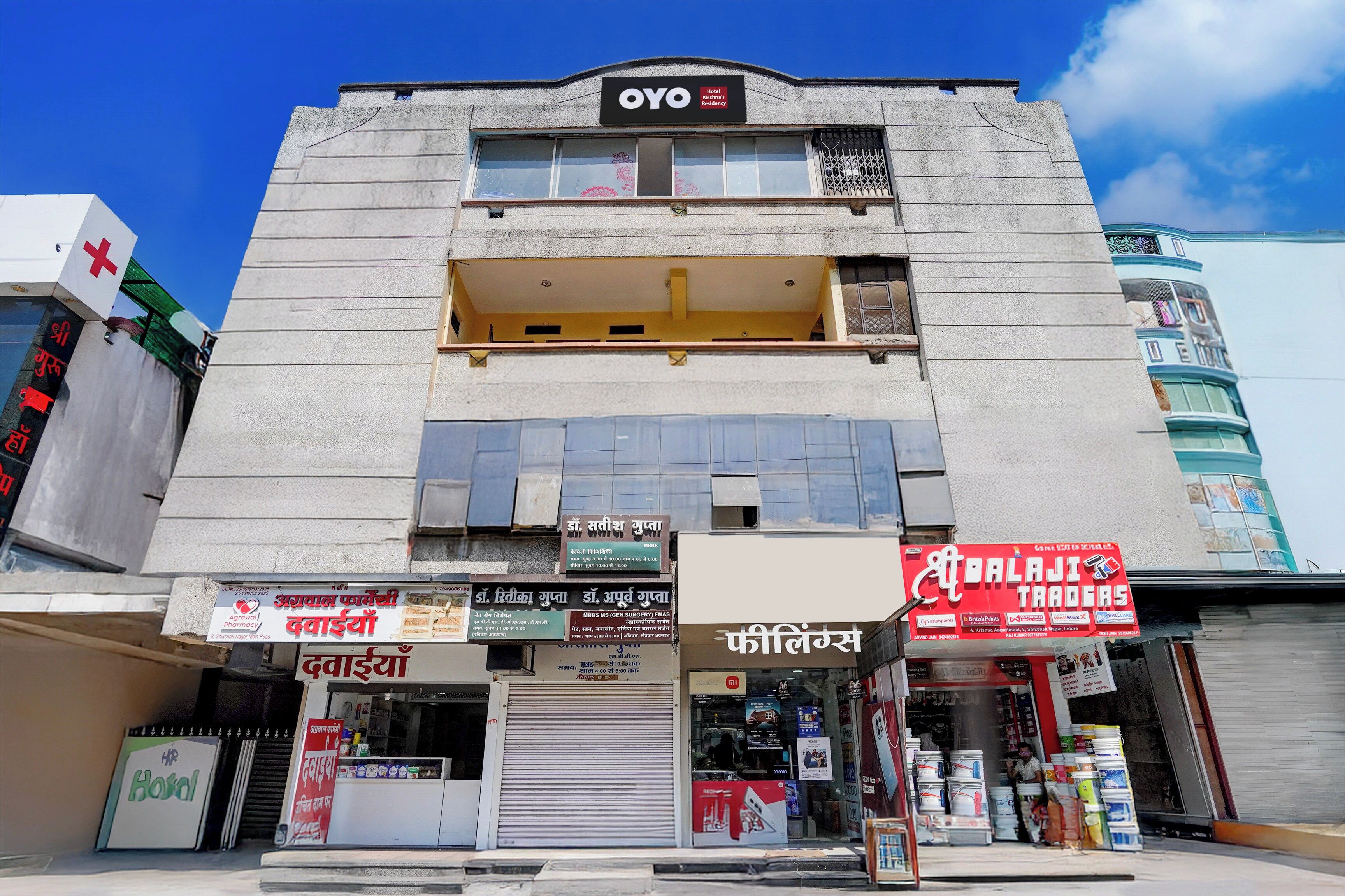 A hotel named 'OYO' with multiple shops on the ground floor, including a pharmacy and a trading store.