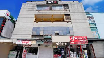 A hotel named 'OYO' with multiple shops on the ground floor, including a pharmacy and a trading store.