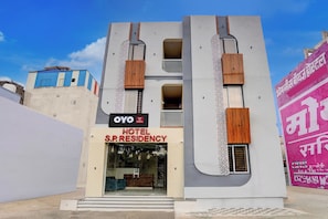 A modern hotel with a prominent 'OYO Hotel S.P. Residency' sign, a large entrance, and a distinctive facade with vertical wooden slats. - Hotel O S.P Residency (Indore)