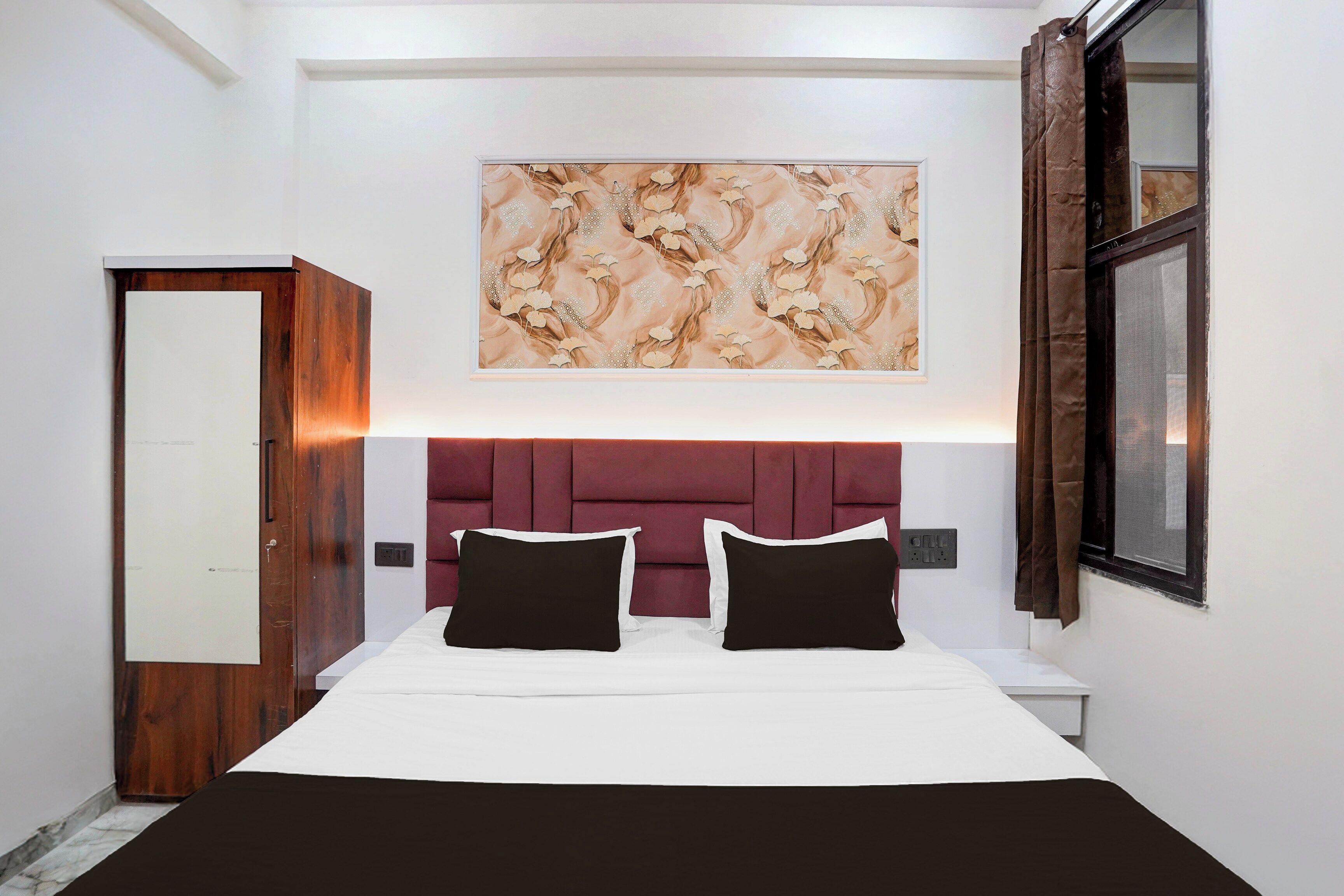 Un dormitorio con una cama grande, cabecera, una obra de arte en la pared, armario y una ventana con cortinas.