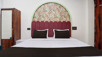 Quarto com uma cama, porta de madeira e parede com desenho de folhas.