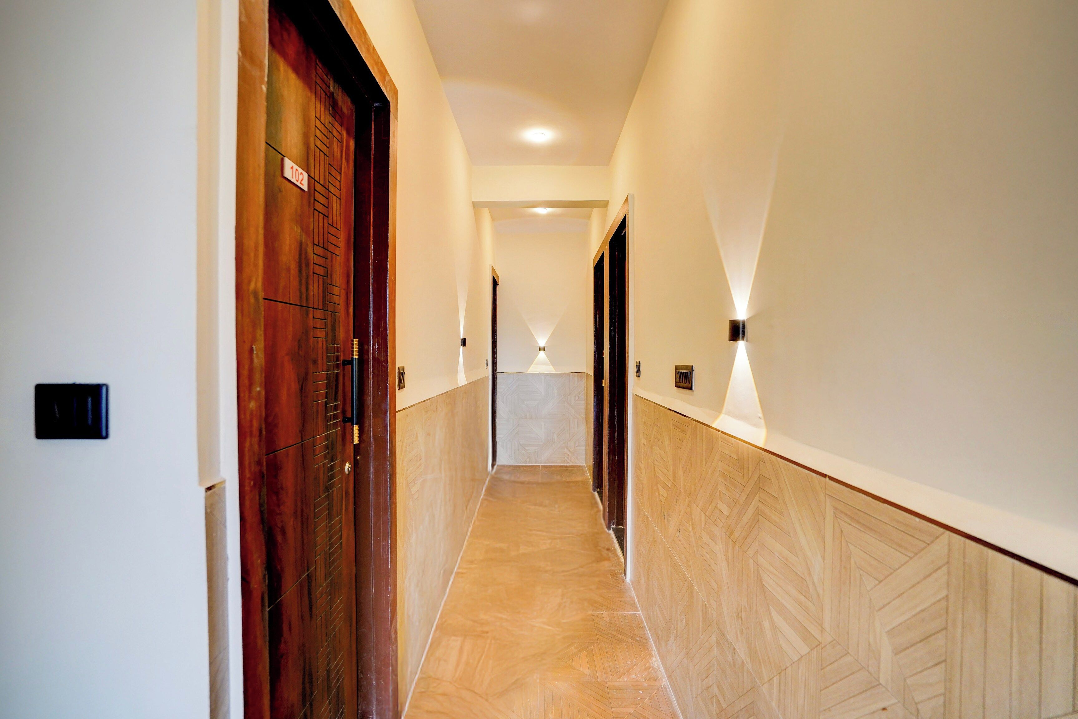 Corredor com portas de madeira e piso em padrão herringbone.