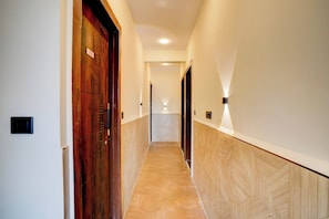 A hallway with wooden doors and a herringbone-patterned floor. - Hotel O S.P Residency (Indore)