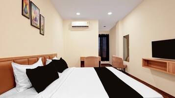 Quarto de hotel com cama, escrivaninha, cadeira, televisão e ar condicionado.