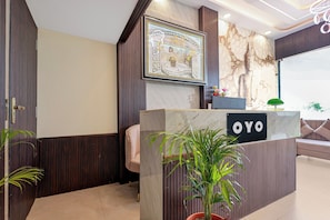 En receptionsdisk med et skilt der viser 'OYO' og et indrammet kunstværk over disken.