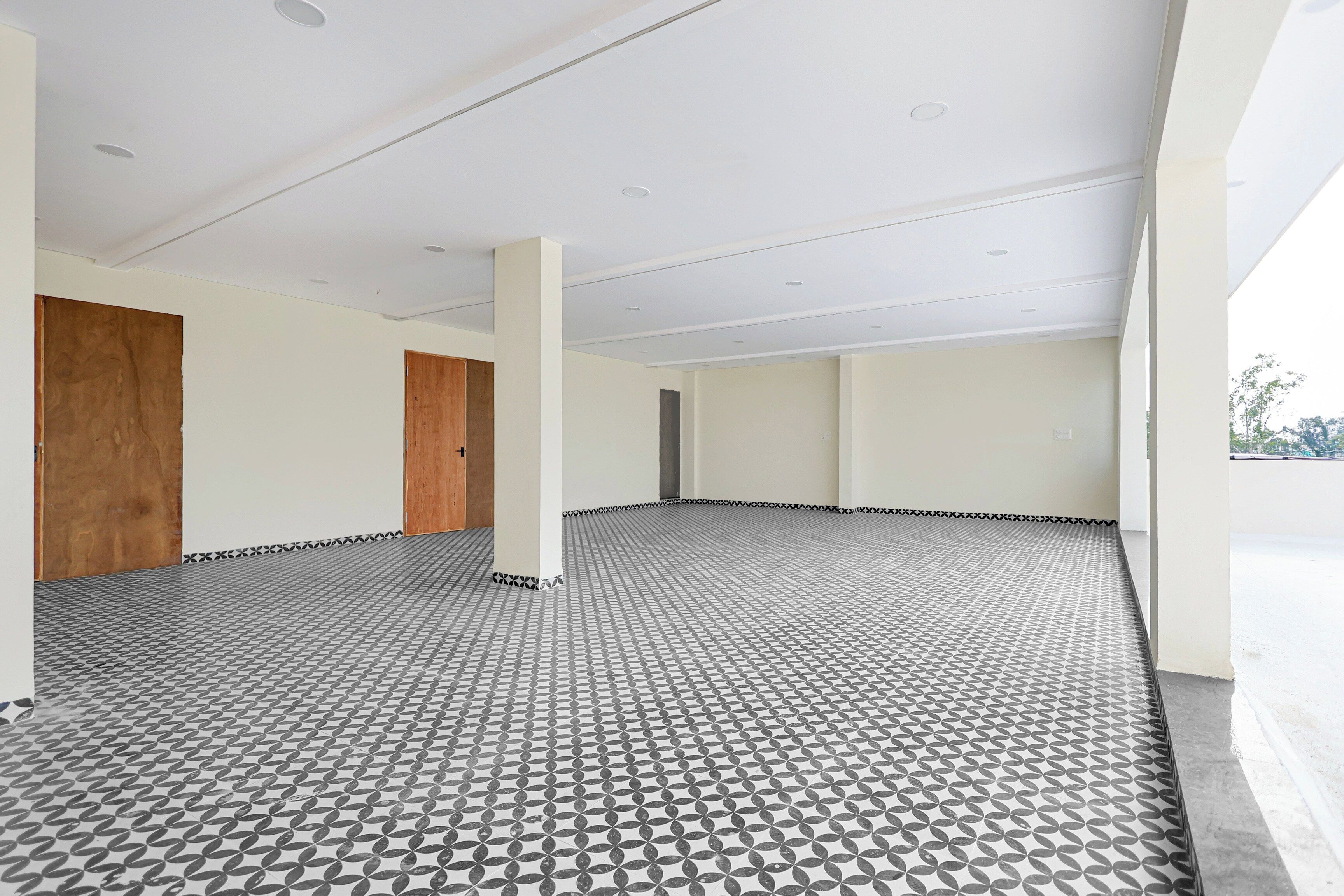 Um quarto amplo com piso estampado, paredes brancas e portas de madeira.