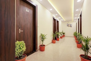 Un pasillo con puertas de madera, con el número 209, y plantas en macetas a lo largo de las paredes.