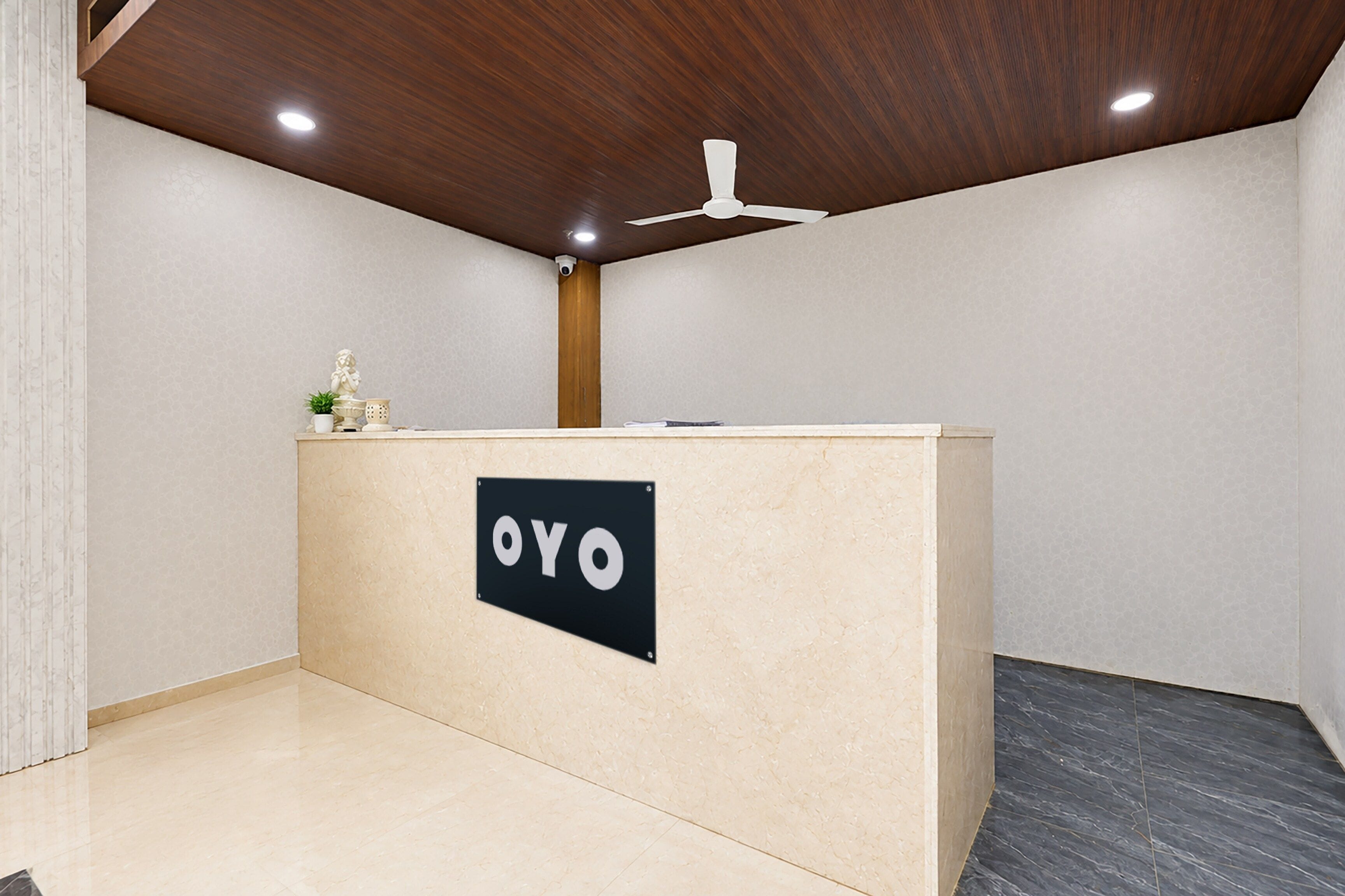 Un mostrador de recepción con un cartel que dice 'OYO' en un interior moderno con techo de madera e iluminación empotrada.
