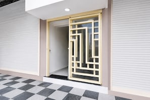 A modern building entrance with a glass door and a checkered floor pattern. - Hotel O Balaji (Indore)