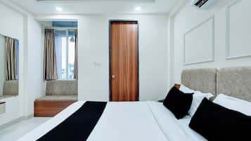 Una habitación de hotel con una cama, un banco, una puerta y un equipo de aire acondicionado.