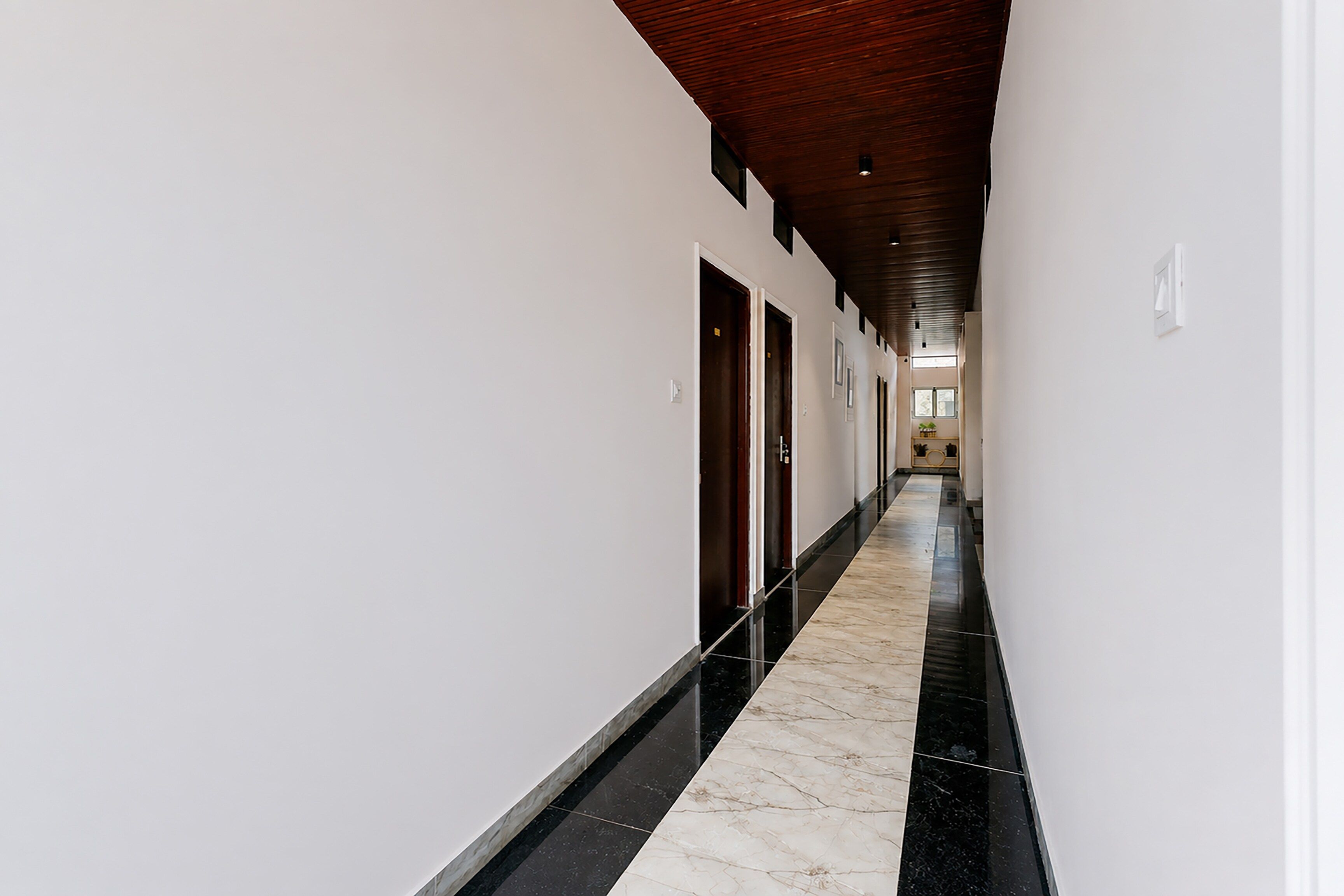 Un pasillo largo y estrecho con techo de madera y paredes blancas.