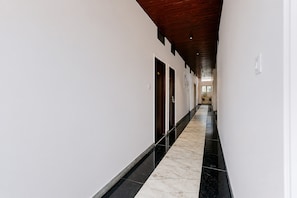 A long, narrow hallway with a wooden ceiling and white walls. - HOTEL O T9T (Indore)