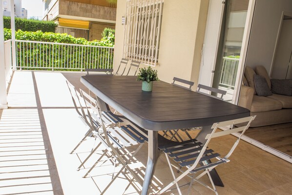 A balcony with a table and chairs, a potted plant, and a sofa.