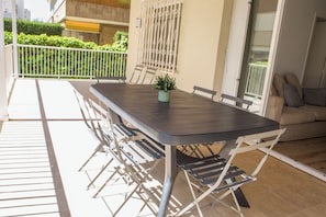 Ein Balkon mit Tisch, Stühlen, einer Zimmerpflanze und einer Couch.