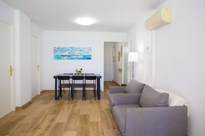 A modern living room with a grey sofa, a dining table with four chairs, and a painting on the wall. - New Listing (Salou)